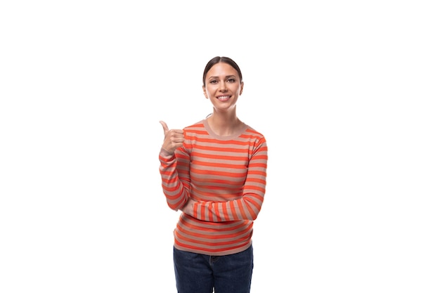 Junge, charmante brünette Dame in einem lässigen gestreiften Pullover lächelt breit auf einem weißen Hintergrund