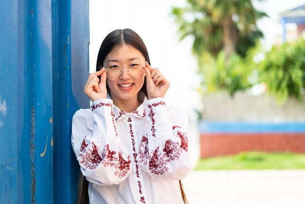 Junge Chinesin im Freien mit Brille mit glücklichem Ausdruck