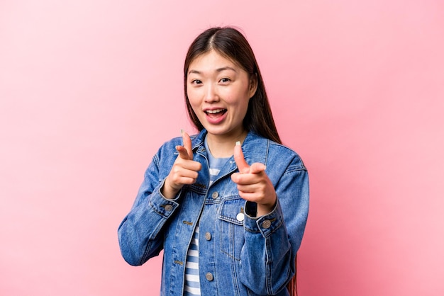 Junge Chinesin isoliert auf rosa Hintergrund, die mit den Fingern nach vorne zeigt