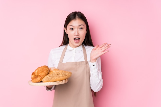 Junge chinesische Bäckerin isoliert überrascht und schockiert.