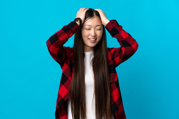 Junge chinesische Frau auf isoliertem blauem Lachen