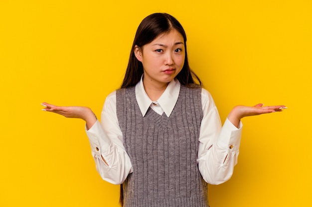 Junge chinesische Frau, die an fragenden Gesten zweifelt und mit den Schultern zuckt.