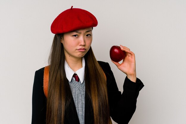 Junge chinesische Frau, die eine Schuluniform trägt, die auf weißer Wand lokalisiert wird