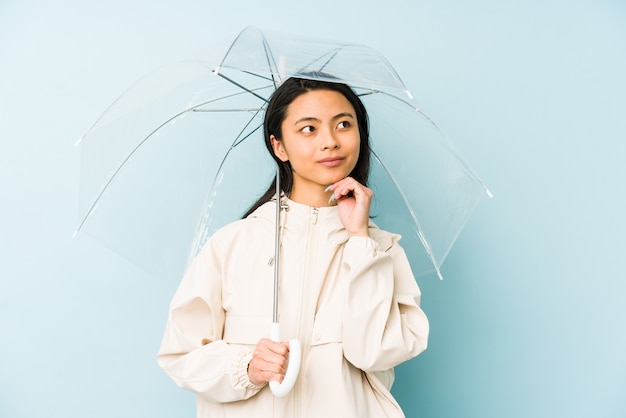 Junge chinesische Frau, die einen isolierten Regenschirm hält, der Nummer eins mit Finger zeigt.