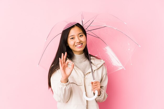 Junge chinesische Frau, die einen Regenschirm hält