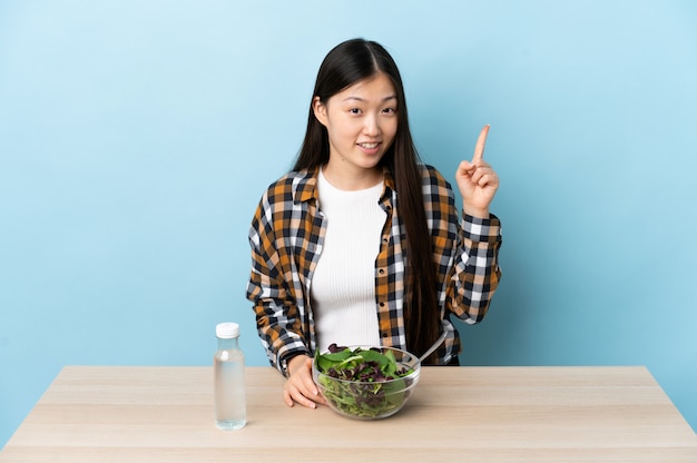 Junge chinesische Frau, die einen Salat isst