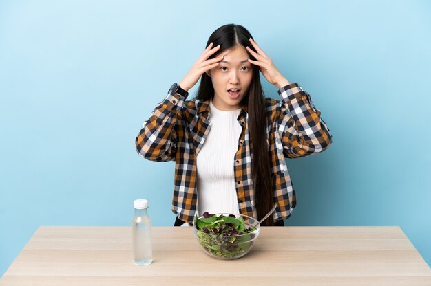 Junge chinesische Frau, die einen Salat mit Überraschungsausdruck isst