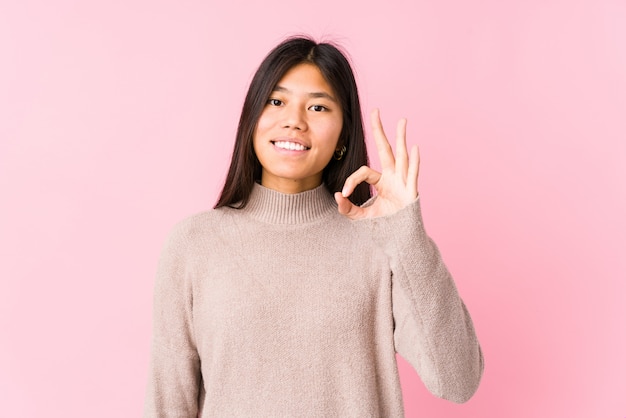 Junge chinesische Frau, die lokalisierte nette und überzeugte darstellende okaygeste aufwirft.