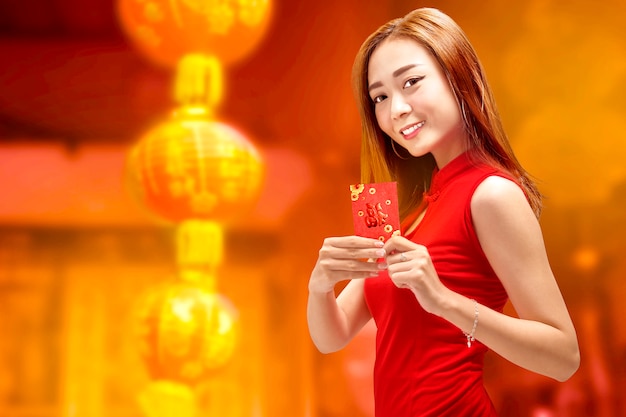 Junge chinesische Frau im cheongsam Kleid, das angpao hält