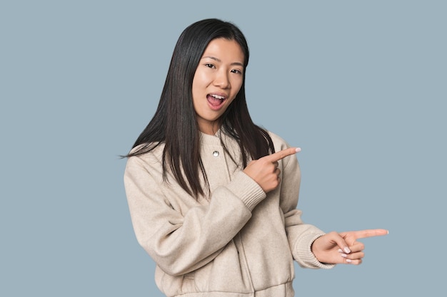 Junge chinesische Frau in einem Studio, die mit dem Zeigefinger auf einen Kopierraum zeigt