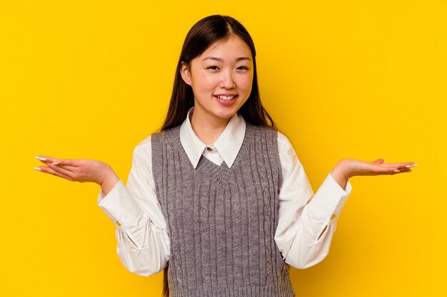 Junge chinesische Frau lokalisiert auf gelber Wand, die einen willkommenen Ausdruck zeigt