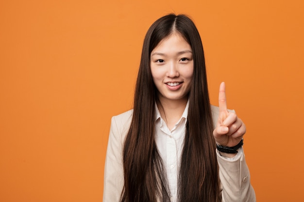 Junge chinesische Geschäftsfrau, die Nummer Eins mit dem Finger zeigt.