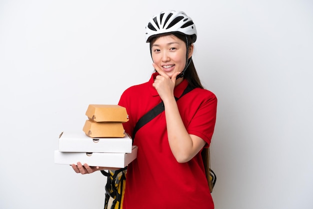 Junge chinesische Lieferfrau, die isoliert auf weißem Hintergrund Essen zum Mitnehmen nimmt, glücklich und lächelnd