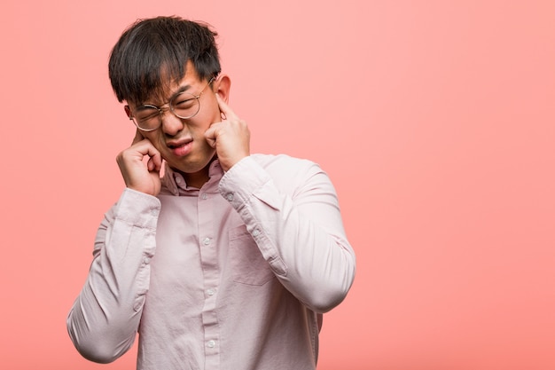 Junge chinesische Mannbedeckungsohren mit den Händen