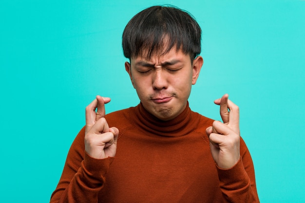 Junge chinesische Mannüberfahrtfinger für das Haben des Glücks