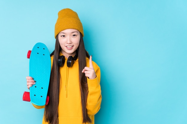 Junge chinesische Skaterfrau isoliert zeigt Nummer über mit Finger.