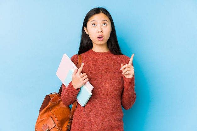 Junge chinesische Studentin isoliert, die oben mit geöffnetem Mund zeigt.