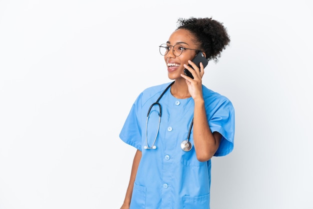 Junge Chirurgin afroamerikanische Ärztin isoliert auf weißem Hintergrund, die ein Gespräch mit dem Handy führt