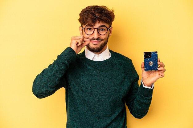 Junge Computerisierer isoliert auf gelbem Hintergrund mit den Fingern auf den Lippen, die ein Geheimnis bewahren.