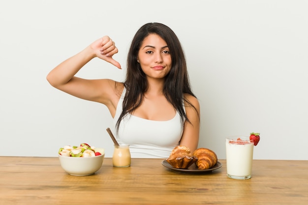 Junge curvy Frau, die ein Frühstück zeigt eine Abneigungsgeste nimmt