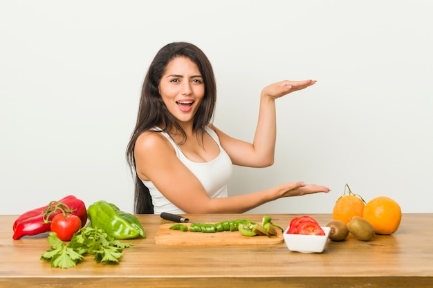 Junge curvy Frau, die eine gesunde Mahlzeit entsetzt und das Halten eines copyspace zwischen Händen überrascht vorbereitet.