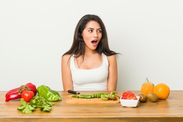 Junge curvy Frau, die eine gesunde Mahlzeit entsetzt wegen etwas vorbereitet, das sie gesehen hat.