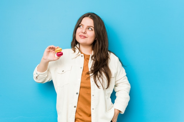 Junge curvy Frau, welche die Makronen träumen vom Erreichen von Zielen und von Zwecken hält