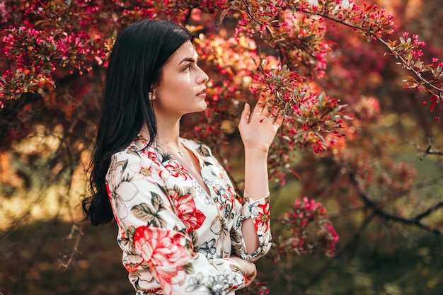 Junge Dame berührt blühenden Baum im Park