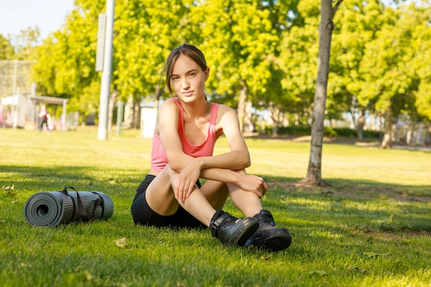 Junge Dame, die auf dem Gras sitzt und in die Kamera schaut