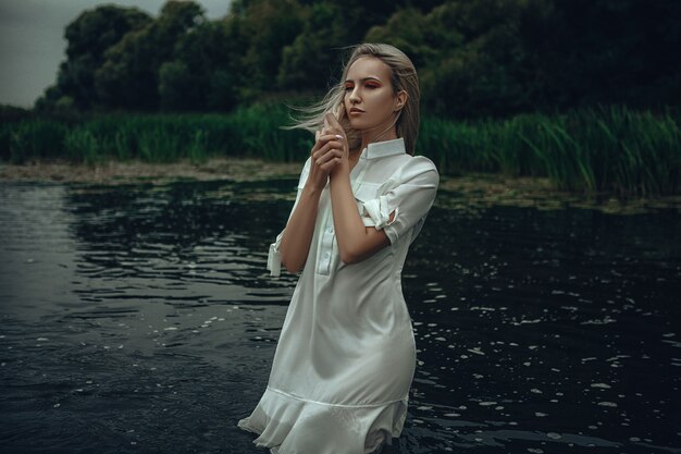 Junge Dame, die ein Kleid trägt, posiert in einem Wasser