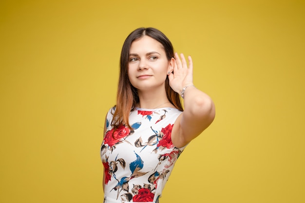 Junge Dame, die Hand nahe Ohr hält und aufmerksam zuhört