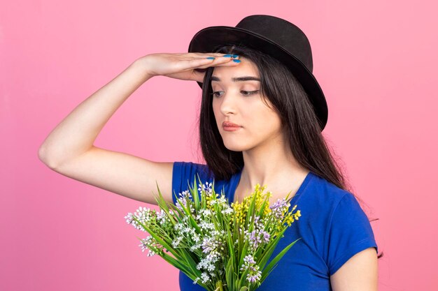 Junge Dame, die Hut trägt und ihre Hand an ihre Stirn hält, während sie wegschaut