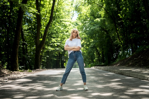 Junge Dame in Jeans und weißem T-Shirt hat eine tolle Zeit in der Natur im Wald. Sommer-