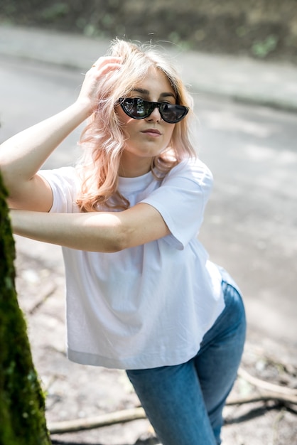 Junge Dame in Jeans und weißem T-Shirt hat eine tolle Zeit in der Natur im Wald. Sommer-