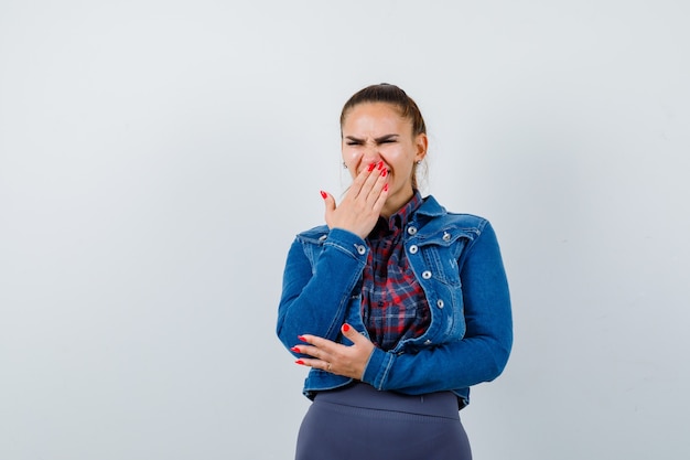 Junge Dame mit der Hand auf dem Mund in Hemd, Jacke und traurigem Blick, Vorderansicht.