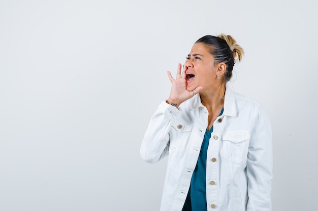 Junge Dame mit der Hand in der Nähe des Mundes, schreit im Hemd, in der weißen Jacke und sieht ängstlich aus, Vorderansicht.