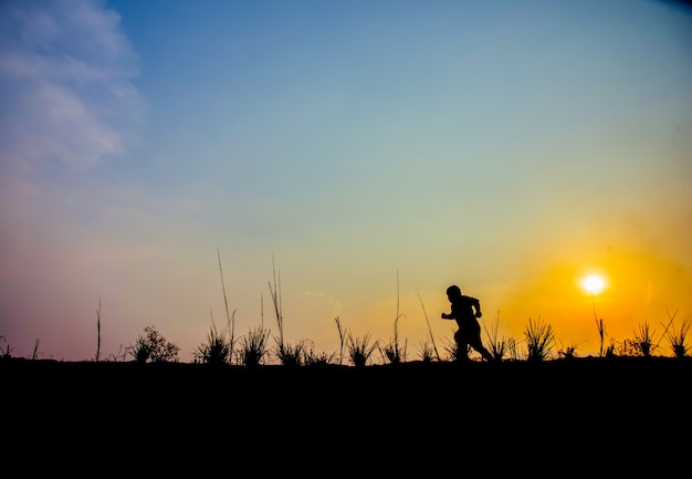 Junge, der auf die Wiese bei Sonnenuntergang geht