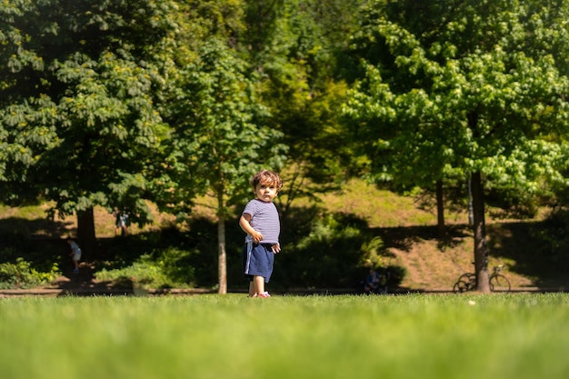 Junge, der Ball in einem Park spielt Erster Schritt und bereits den Ball tretend, der Spaß hat