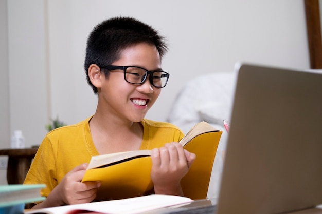 Junge, der Computer und mobiles Gerät verwendet, um online zu studieren. Bildung und Online-Lernen.