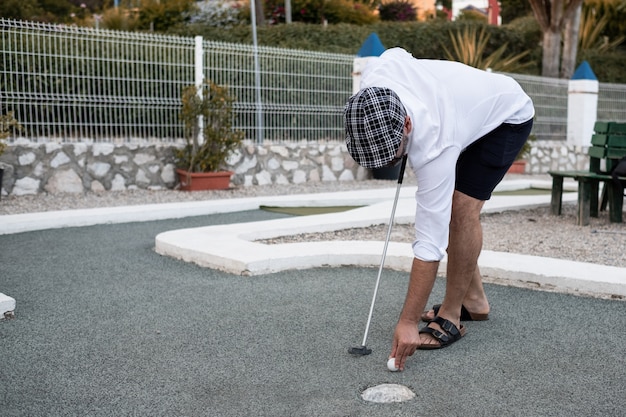 Junge, der den Golfball setzt, um zu werfen