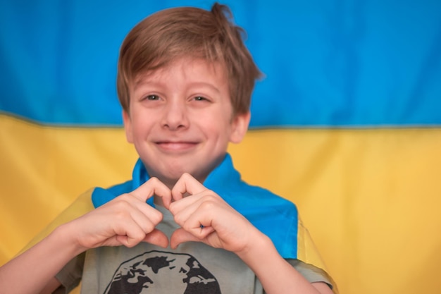 Junge, der die ukrainische gelbblaue Flagge in den Händen hält, unterstützt die Ukraine, indem er Herz zeigt