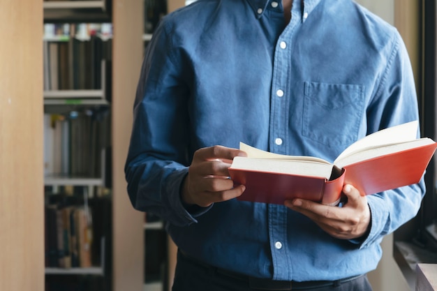 Junge, der ein Buch an der öffentlichen Bibliothek liest