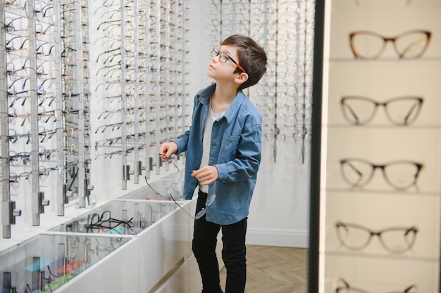 Junge, der eine Brille im Optikgeschäft auswählt