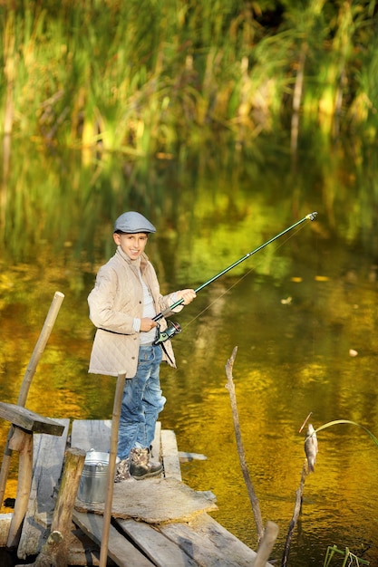 Junge, der einen Fisch vom hölzernen Dock fängt