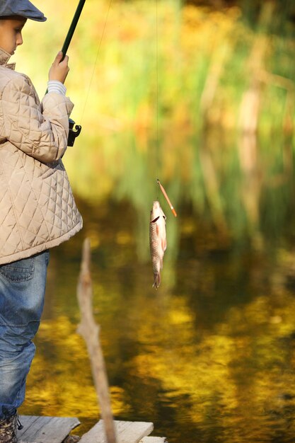 Junge, der einen Fisch vom hölzernen Dock fängt