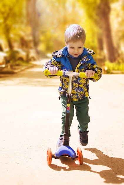 Foto junge, der einen roller im goldenen herbst reitet