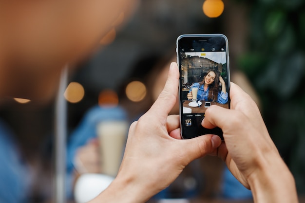 Junge, der Fotos von einem Mädchen in einem Kaffeehaus macht