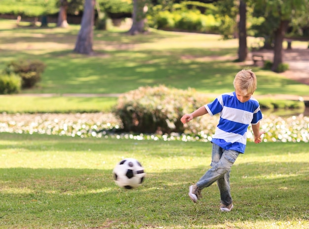 Junge, der Fußball im Park spielt