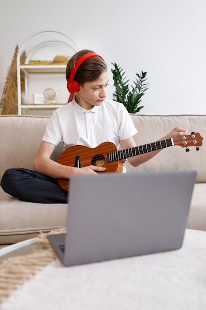 Junge, der Gitarre spielt und Lektion auf Video zu Hause aufzeichnet