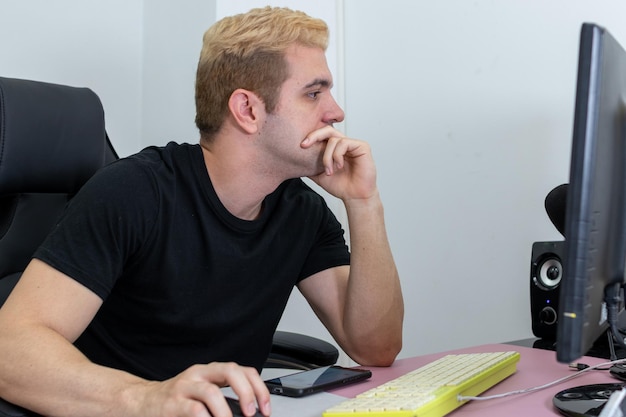 Foto junge, der im büro am computer mit konzentriertem gesicht arbeitet